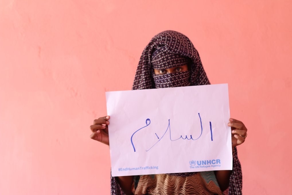 19-year-old Amuna from the host community holds up a sign saying "Peace” during the UNHCR campaign against human trafficking in east Sudan. 