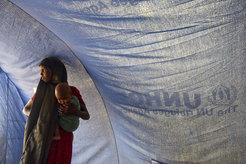 A Somali refugee stands inside a tent with her baby in Dollo Ado, Ethiopia.Fleeing drought and famine in their home country, thousands of Somalis have taken up residence across the border in Dollo Ado where a complex of camps is assisted by the UN Refugee Agency (UNHCR).